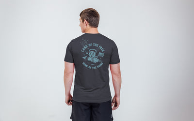 Model posing with a back view of the REP Men's Liberty Bell Tri-Blend Crew T-Shirt in Black and graphic in Blue