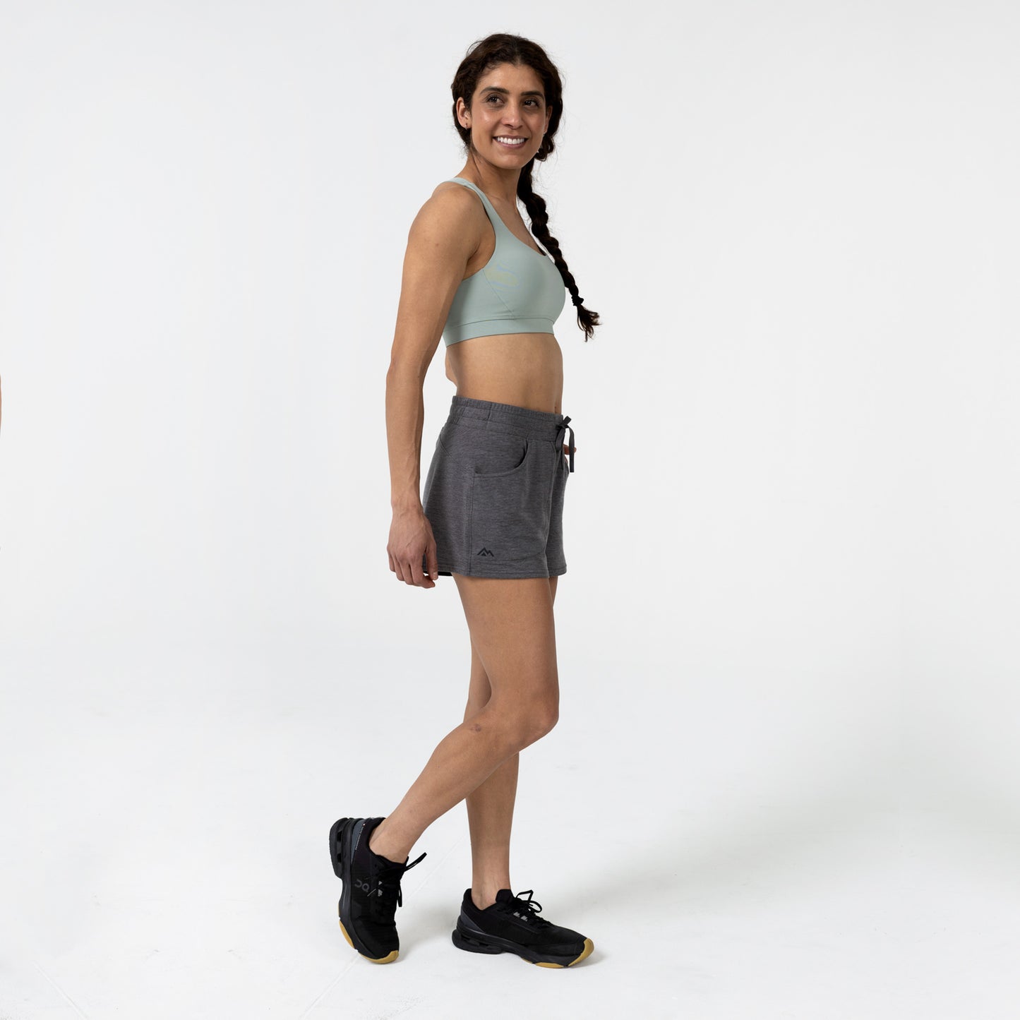 Woman wearing a sports bra and  gray Women's Vellus shorts on a white background