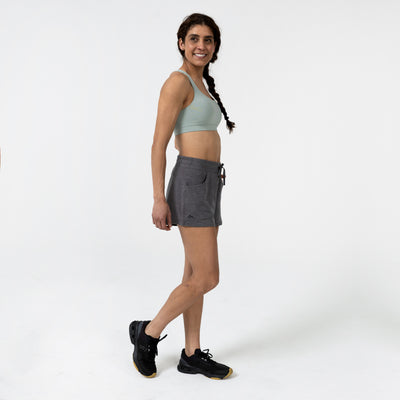 Woman wearing a sports bra and  gray Women's Vellus shorts on a white background