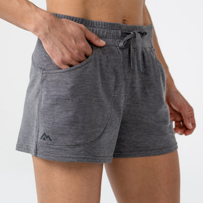 Person wearing gray Women's Vellus athletic shorts on a plain background. Featuring the hand pocket. 