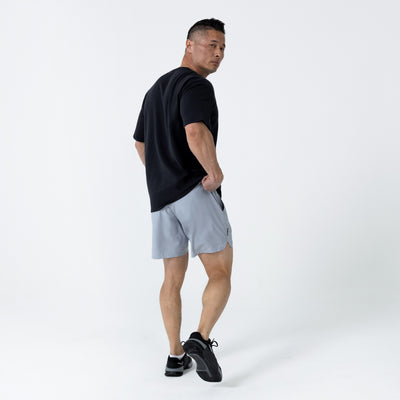 Men's Magnis Heavyweight T-Shirt in Black on person with grey shorts on a white background. back profile.