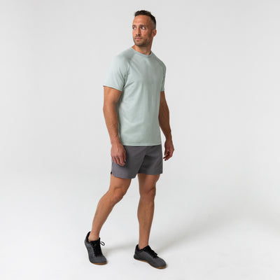 Man wearing an aqua gray Men's Aerix  t-shirt and shorts on a white background