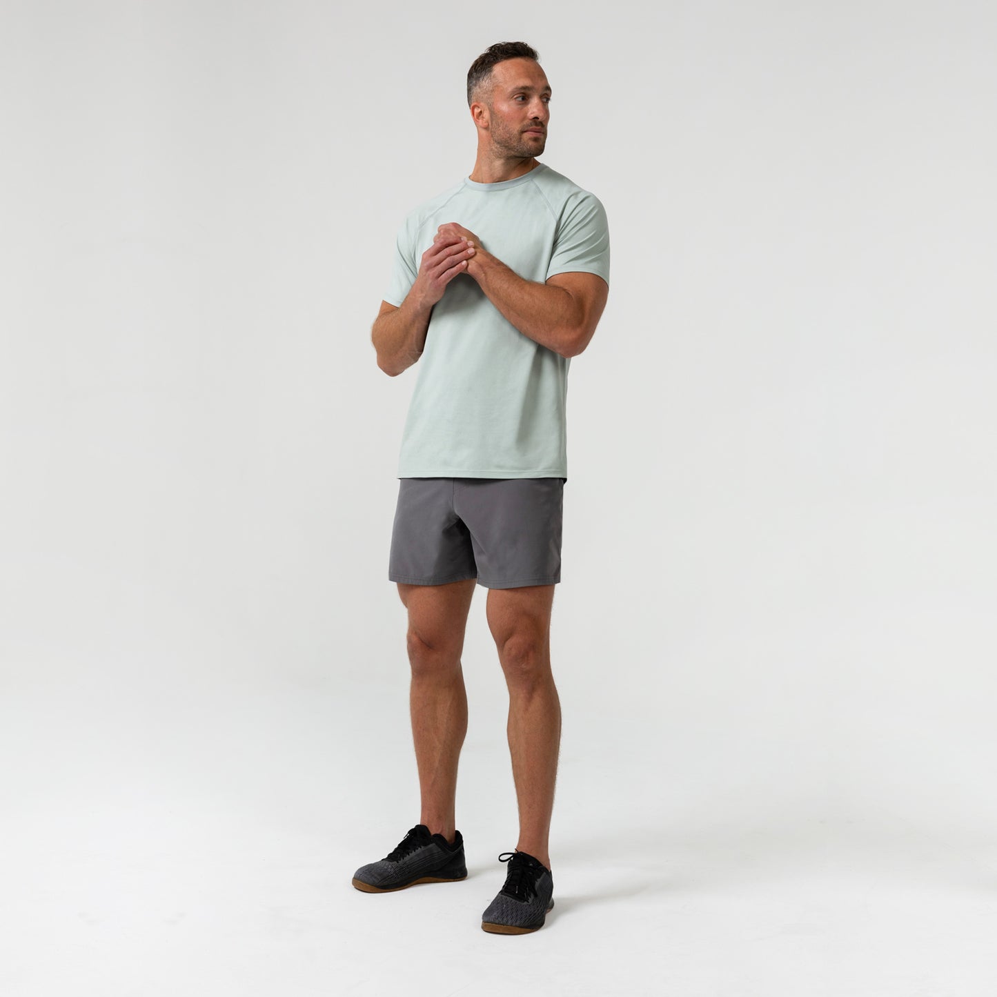 Man wearing an aqua gray Men's Aerix  t-shirt and shorts on a white background