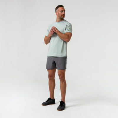 Man wearing an aqua gray Men's Aerix  t-shirt and shorts on a white background