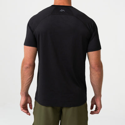 Person wearing a black Men's Aerix athletic shirt with a mountain logo on the back, standing against a light background.