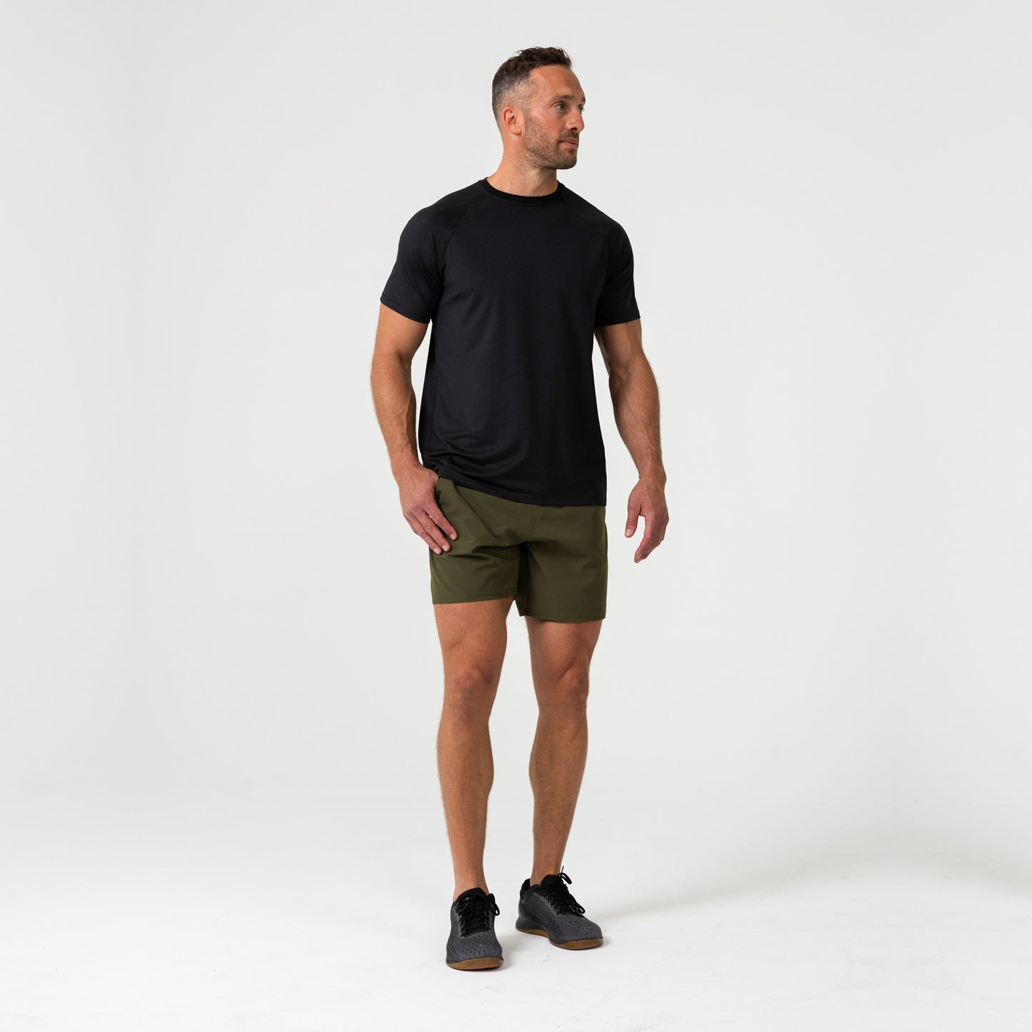 Man wearing a black Men's Aerix  t-shirt and green shorts on a white background