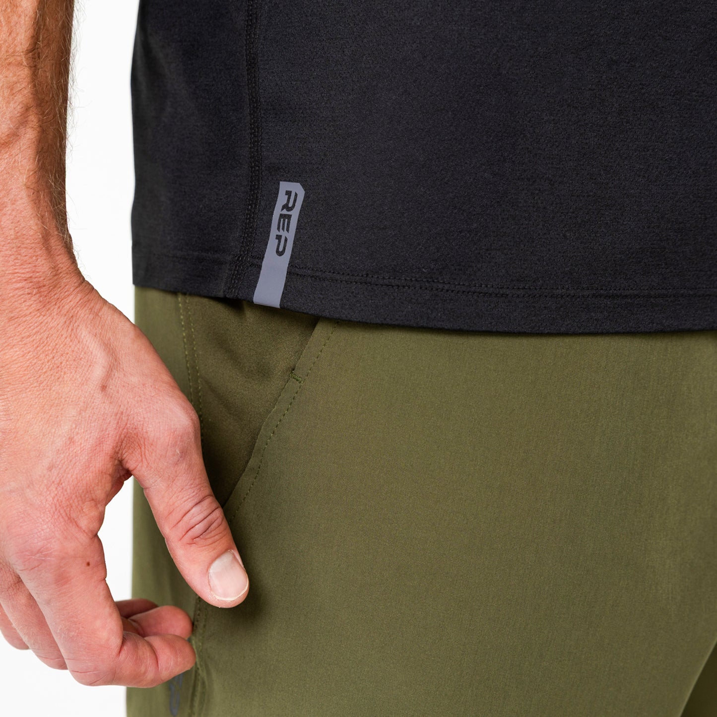 Person wearing a black Men's Aerix shirt with a visible brand logo on the side and green shorts.