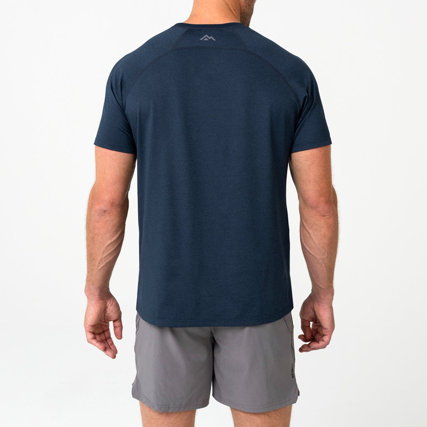 Person wearing a navy Men's Aerix athletic shirt with a mountain logo on the back, standing against a light background.