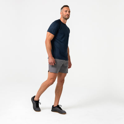 Man wearing an navy Men's Aerix  t-shirt and shorts on a white background