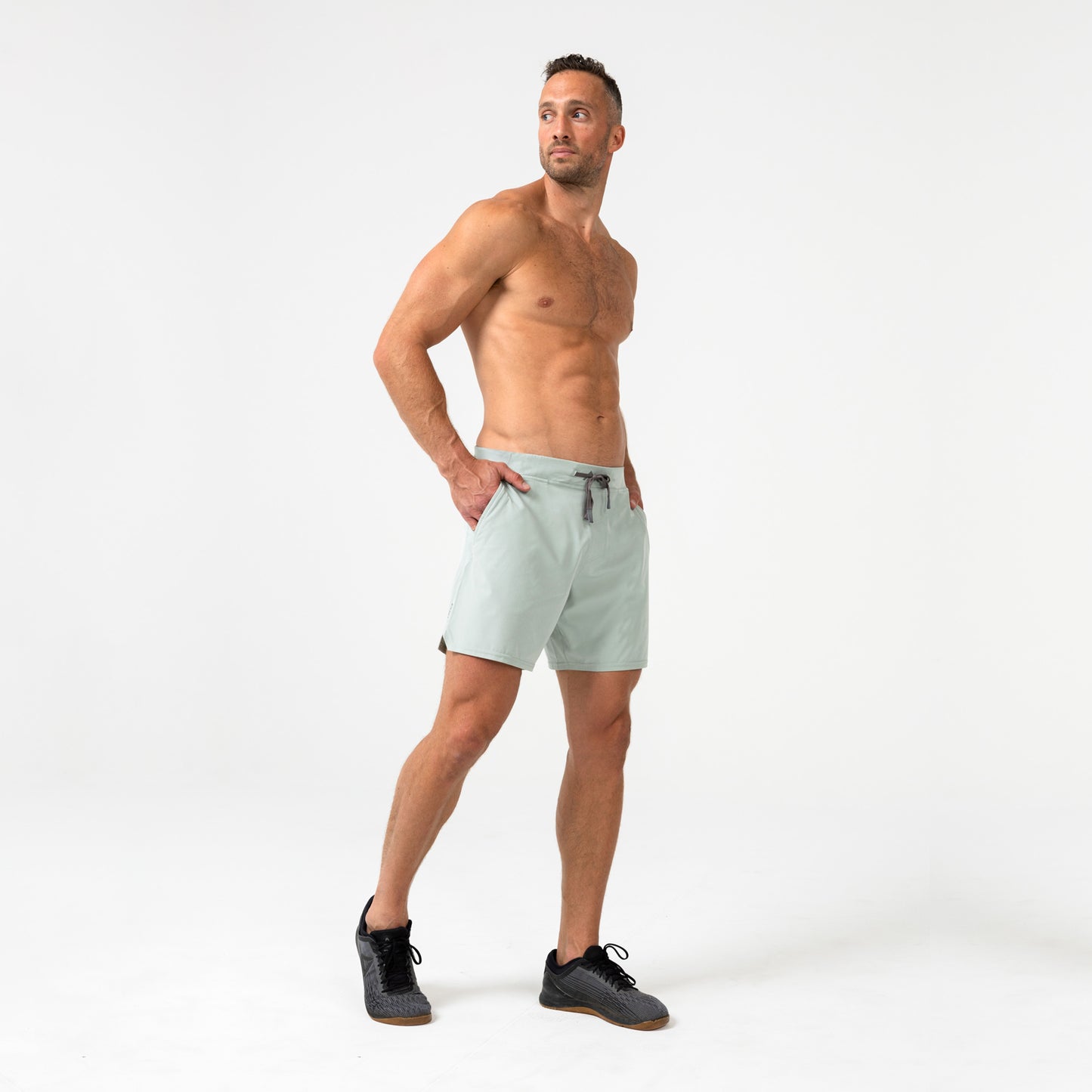Man wearing the Pinnacle Shorts in Aqua Gray on a light background showing off the pockets
