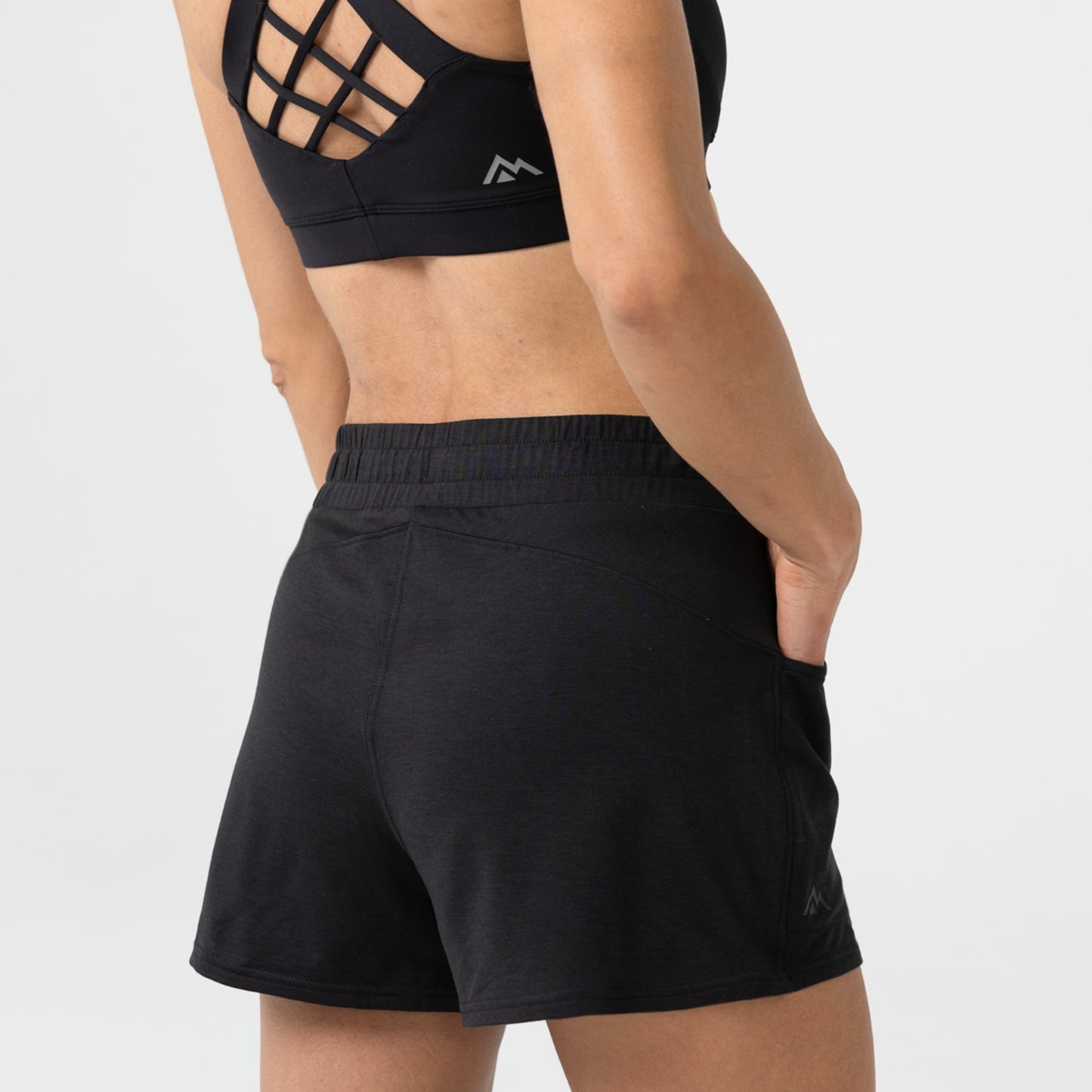 Person wearing black Women's Vellus athletic shorts (back view) and sports bra on a background