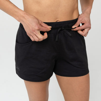 Person wearing black Women's Vellus shorts on a plain background. Showing drawstring.