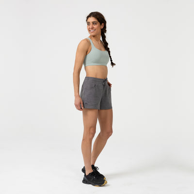 Woman wearing a sports bra and  gray Women's Vellus shorts on a white background