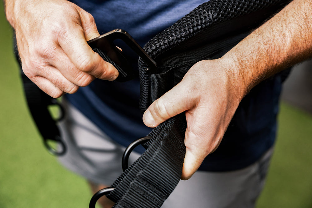 Showing  a person putting on the belt squat belt and the g-hook mechanism.