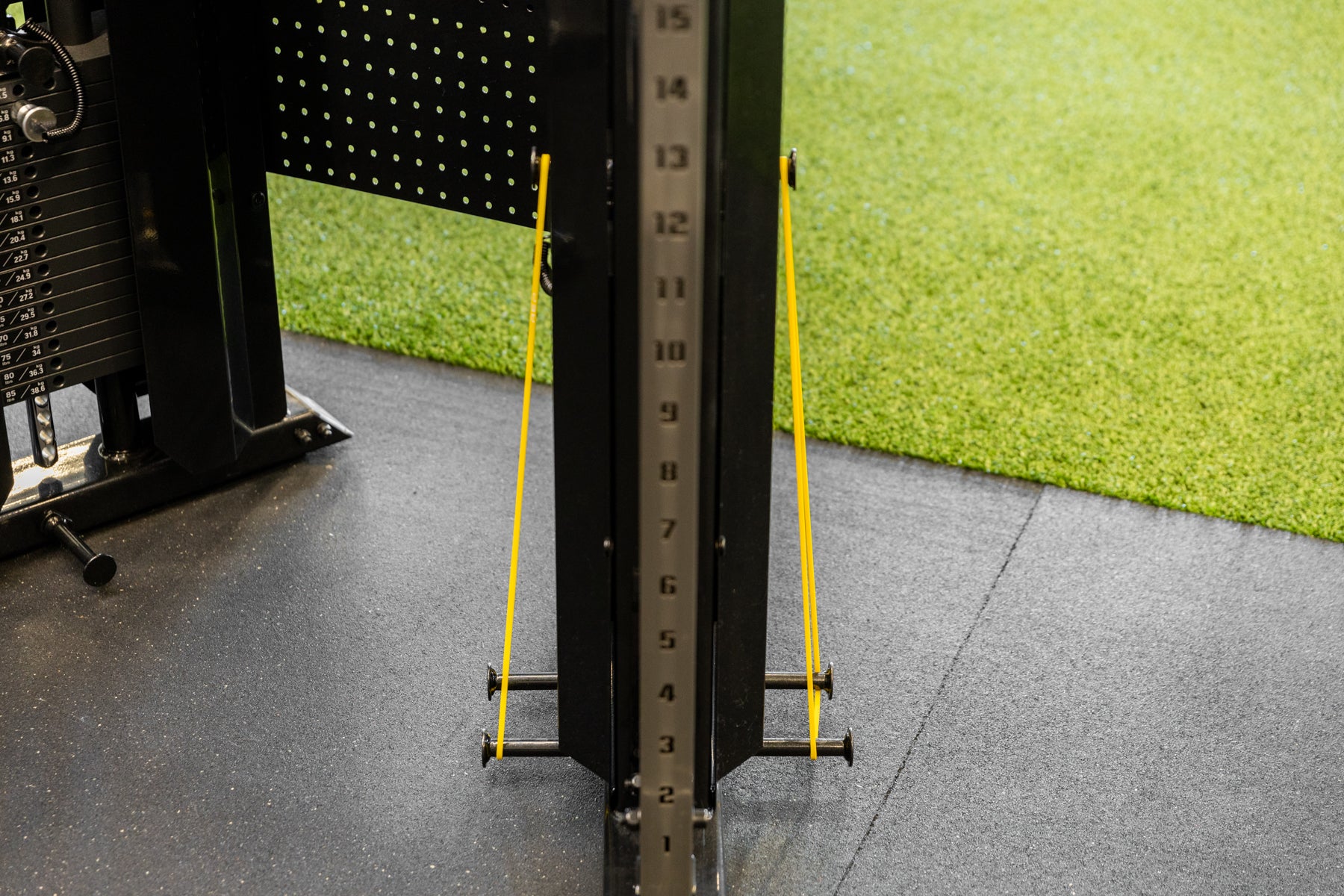 Yellow short resistance bands attached to the band pegs of the REP Arcadia Functional Trainer for added resistance.