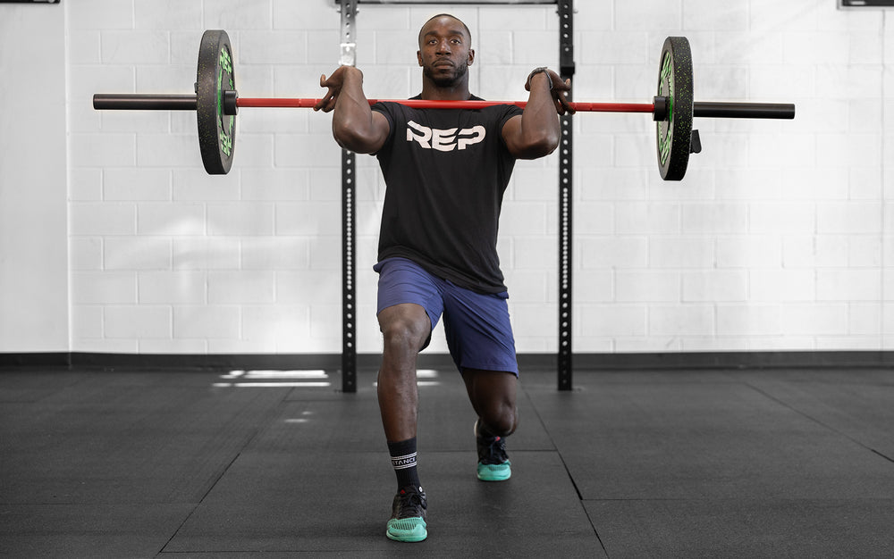 Male lifter performing a front racked forward lunge with a loaded REP 20kg Colorado Bar.