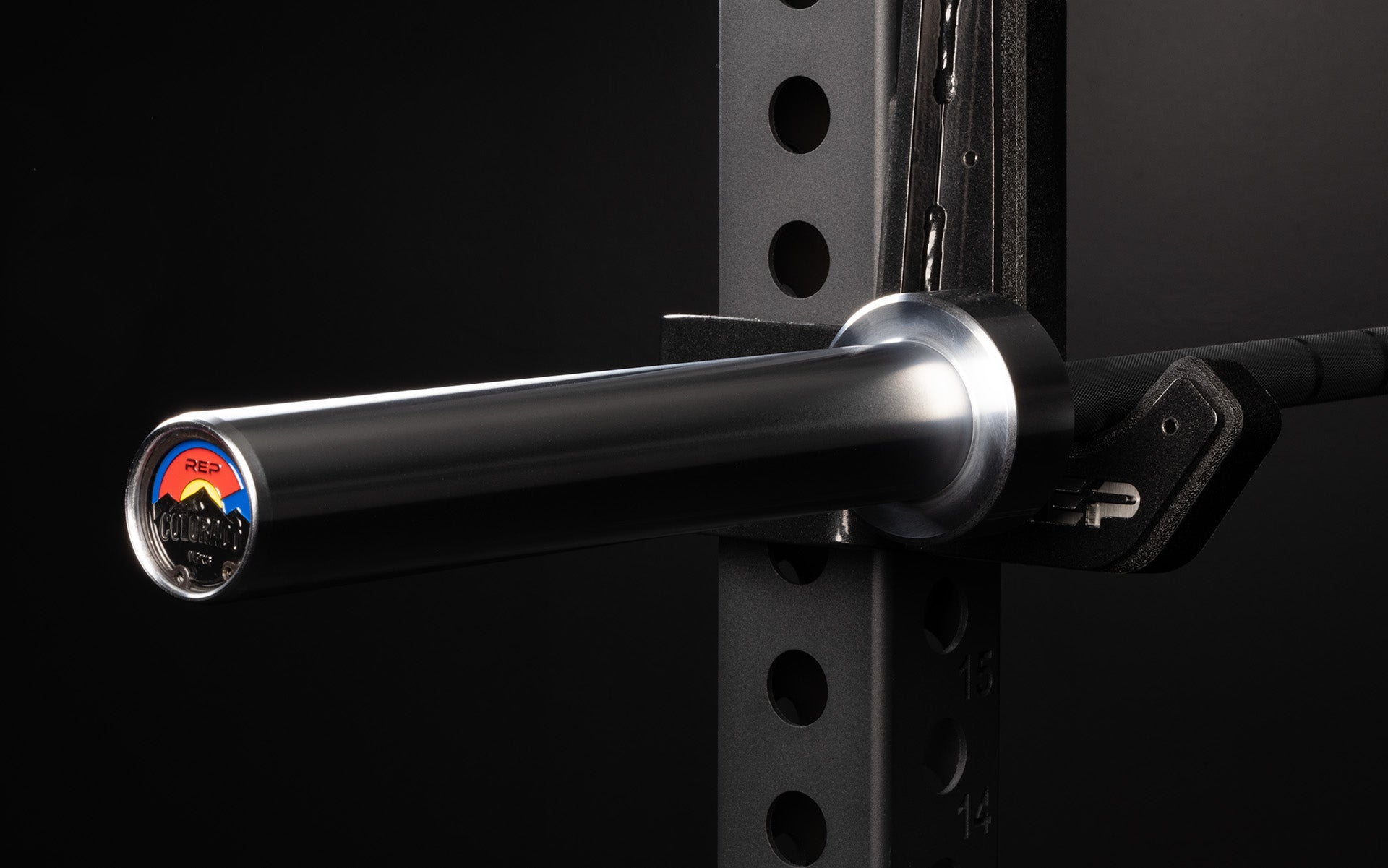 Close-up view of the sleeve and premium endcap of a racked REP 15kg Colorado Bar.