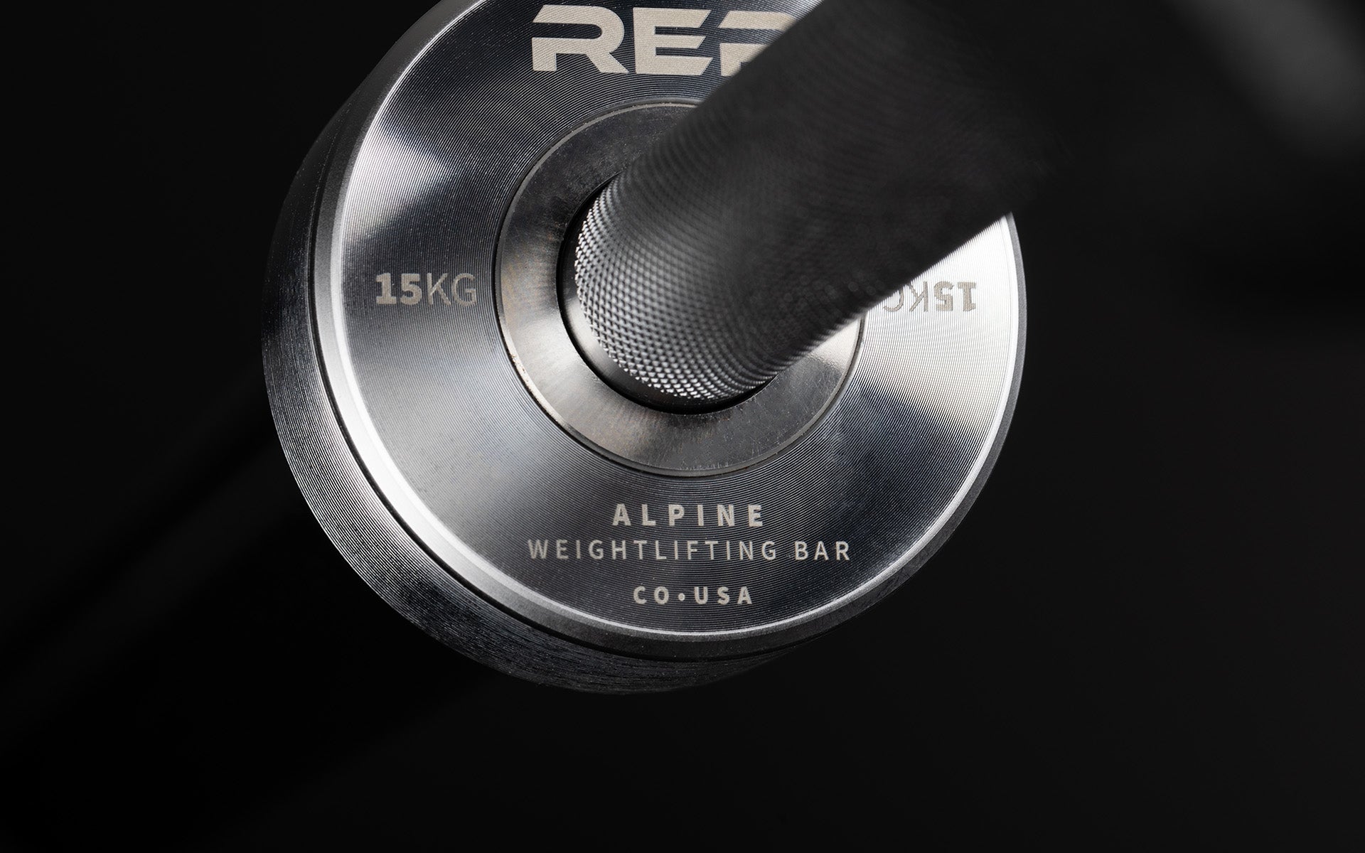 Close-up view of the laser-etched labeling on the inside of the sleeve of a REP 15kg Alpine Weightlifting Bar.