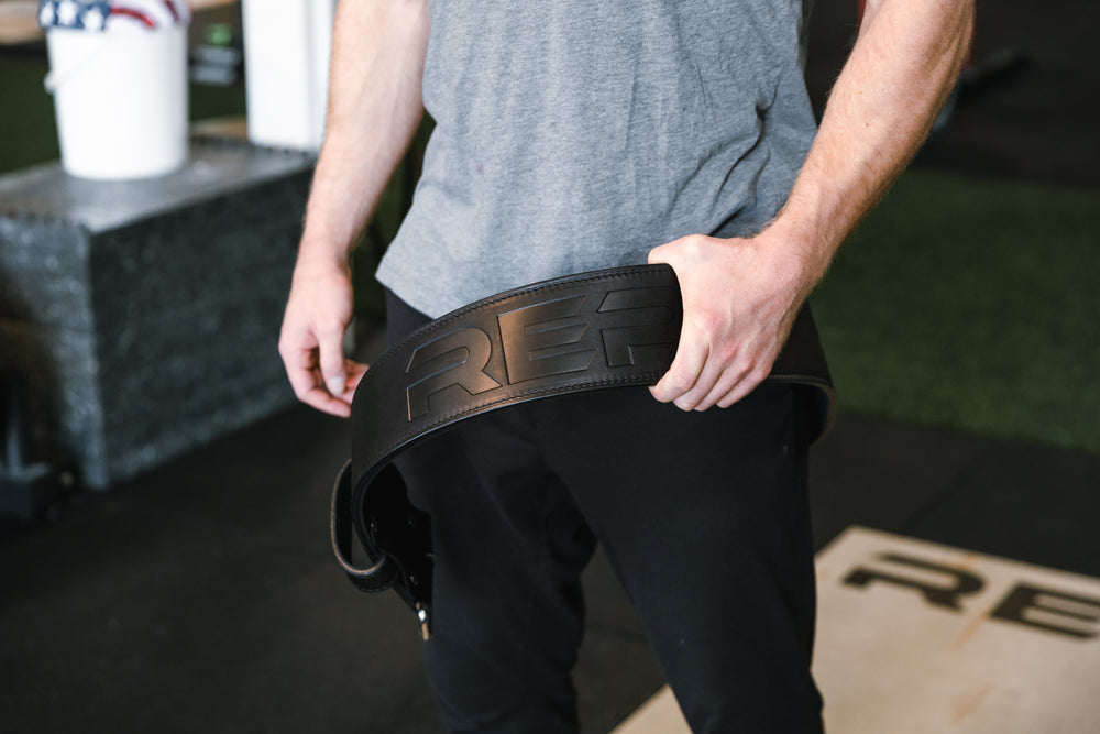 Athlete putting on the black REP Premium Leather Lifting Belt.