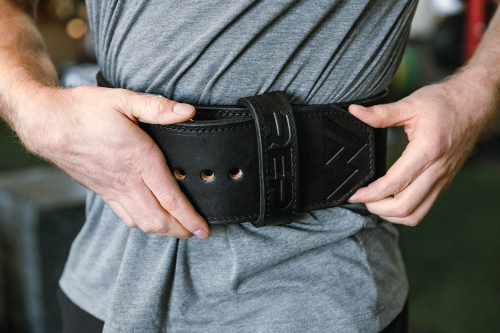 Athlete putting on the black REP Premium Leather Lifting Belt.