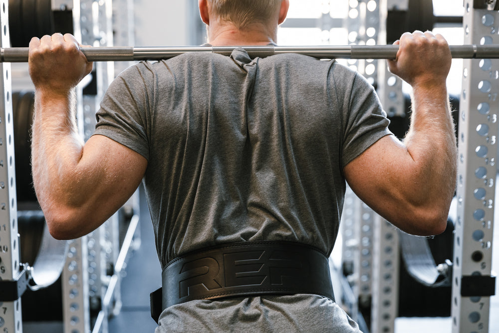 Athlete performing a back squat while wearing a black REP Premium Leather Lifting Belt.