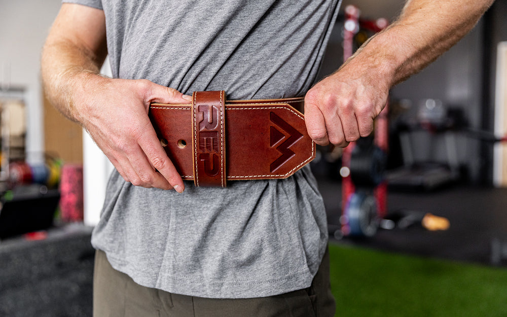 Athlete putting on the brown REP Premium Leather Lifting Belt.