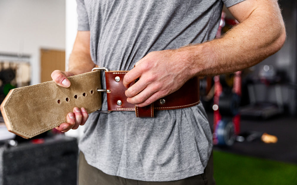 Athlete putting on the brown REP Premium Leather Lifting Belt.