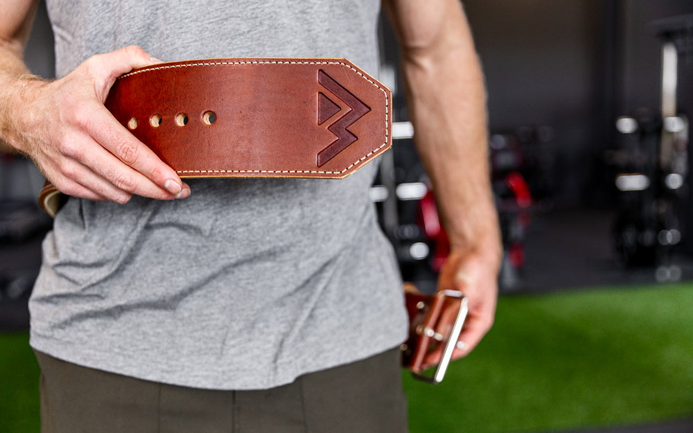 Athlete putting on the brown REP Premium Leather Lifting Belt.