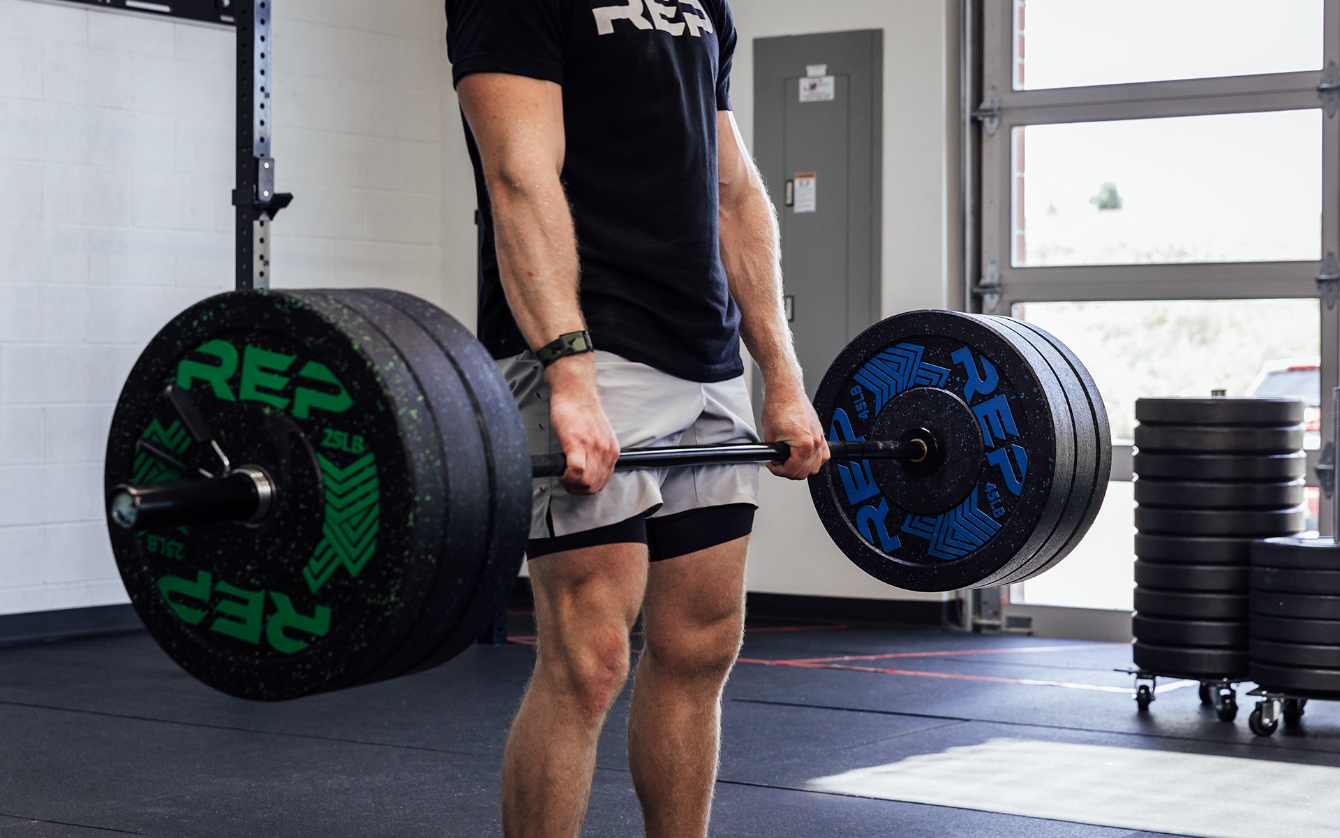 Close-up view of a male lifter at the finish position of a deadlift using a loaded REP Black Canyon Bar - 20kg.