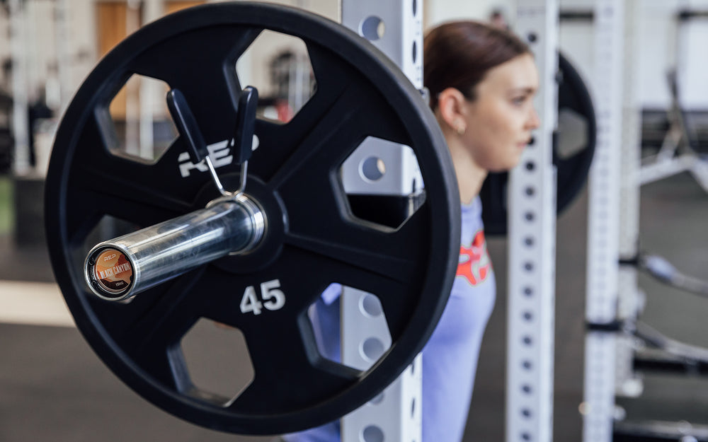 Female lifter preparing to unrack a loaded REP 15kg Black Canyon Bar to back squat.