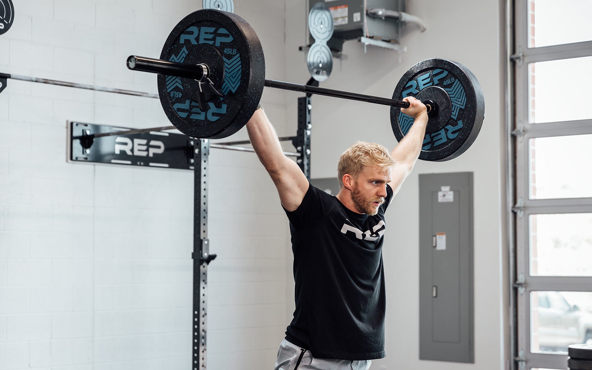 Male lifter at the top of an overhead squat using a loaded REP Black Canyon Bar - 20kg.