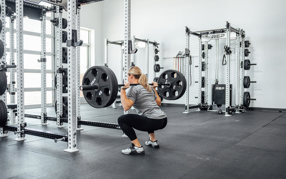 Female lifter performing a back squat with a loaded 15kg Colorado Bar.