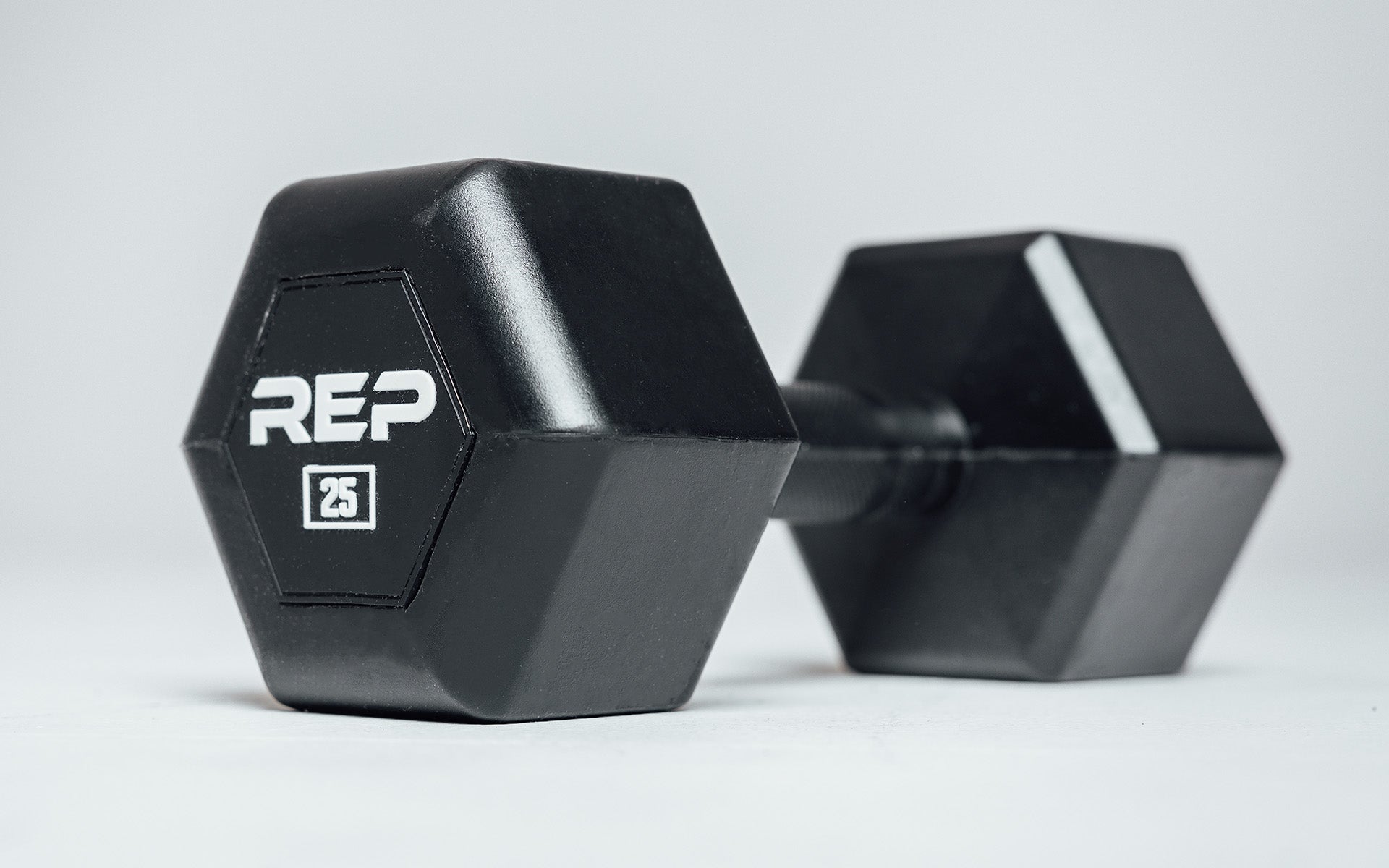 Angled view of a 25lb Rubber Coated Hex Dumbbell showing off the white 