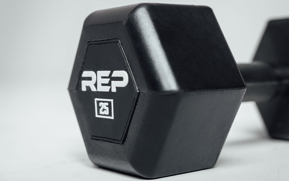 Close-up view of the hexagon head of a 25lb Rubber Coated Hex Dumbbell showing off the white "REP" logo and weight marking.