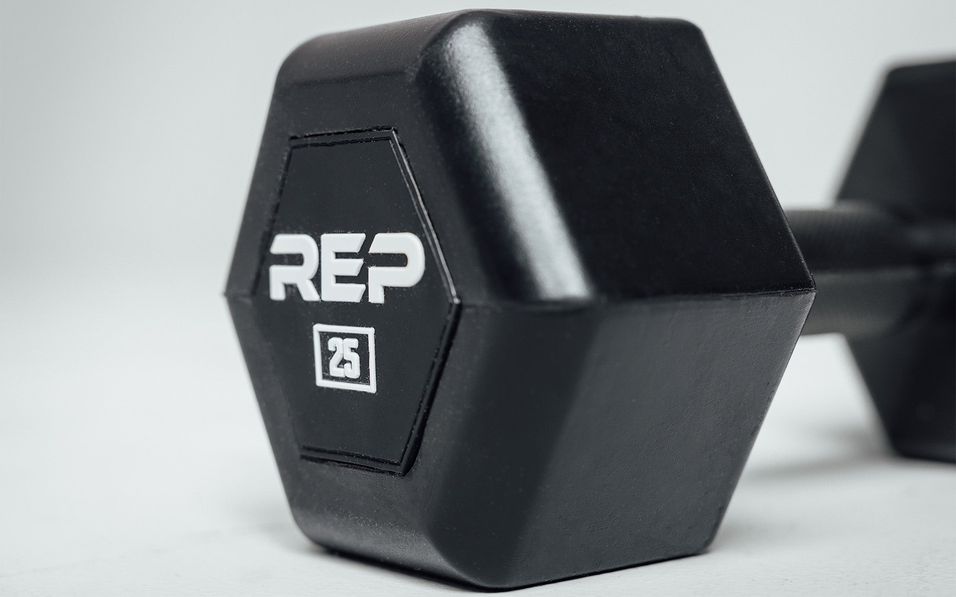 Close-up view of the hexagon head of a 25lb Rubber Coated Hex Dumbbell showing off the white 