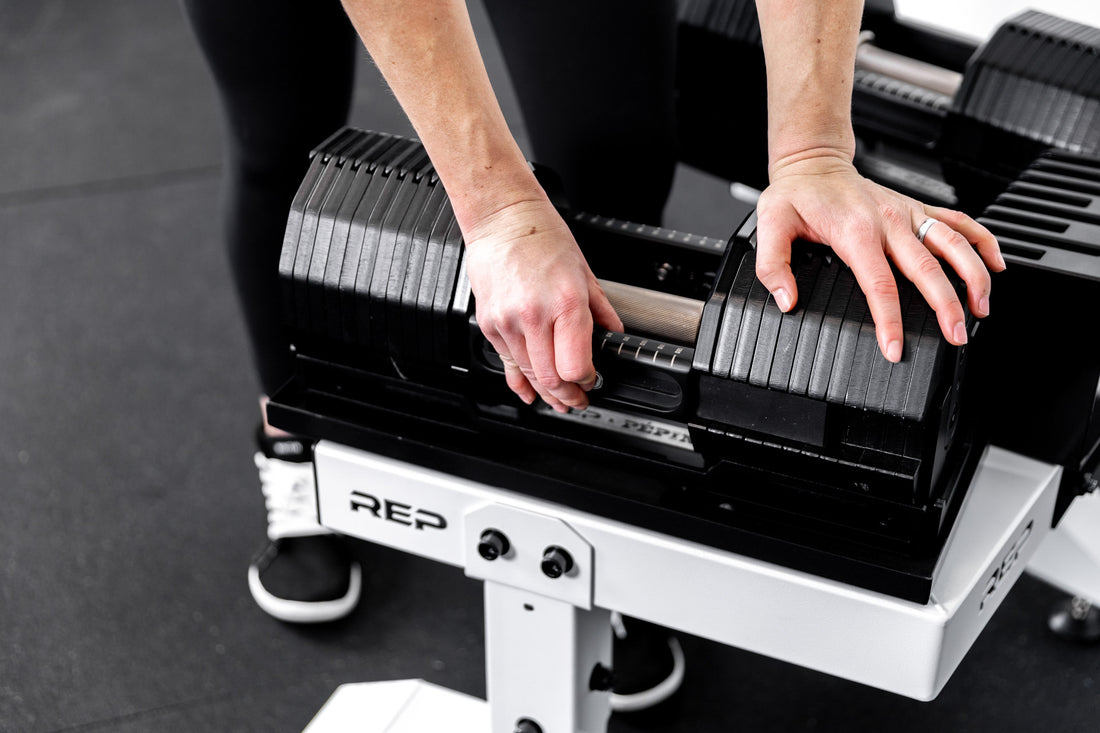 Athlete adjusting the weight on the REP x PÉPIN FAST Series Adjustable Dumbbell while it is sitting on the Adjustable Dumbbell Stand.