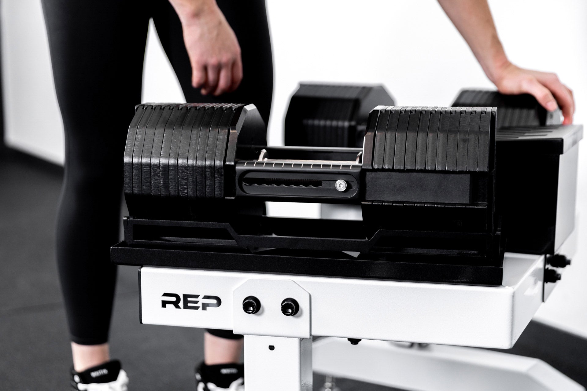 REP® x PÉPIN™ adjustable dumbbells on a white REP® Adjustable Dumbbell Stand