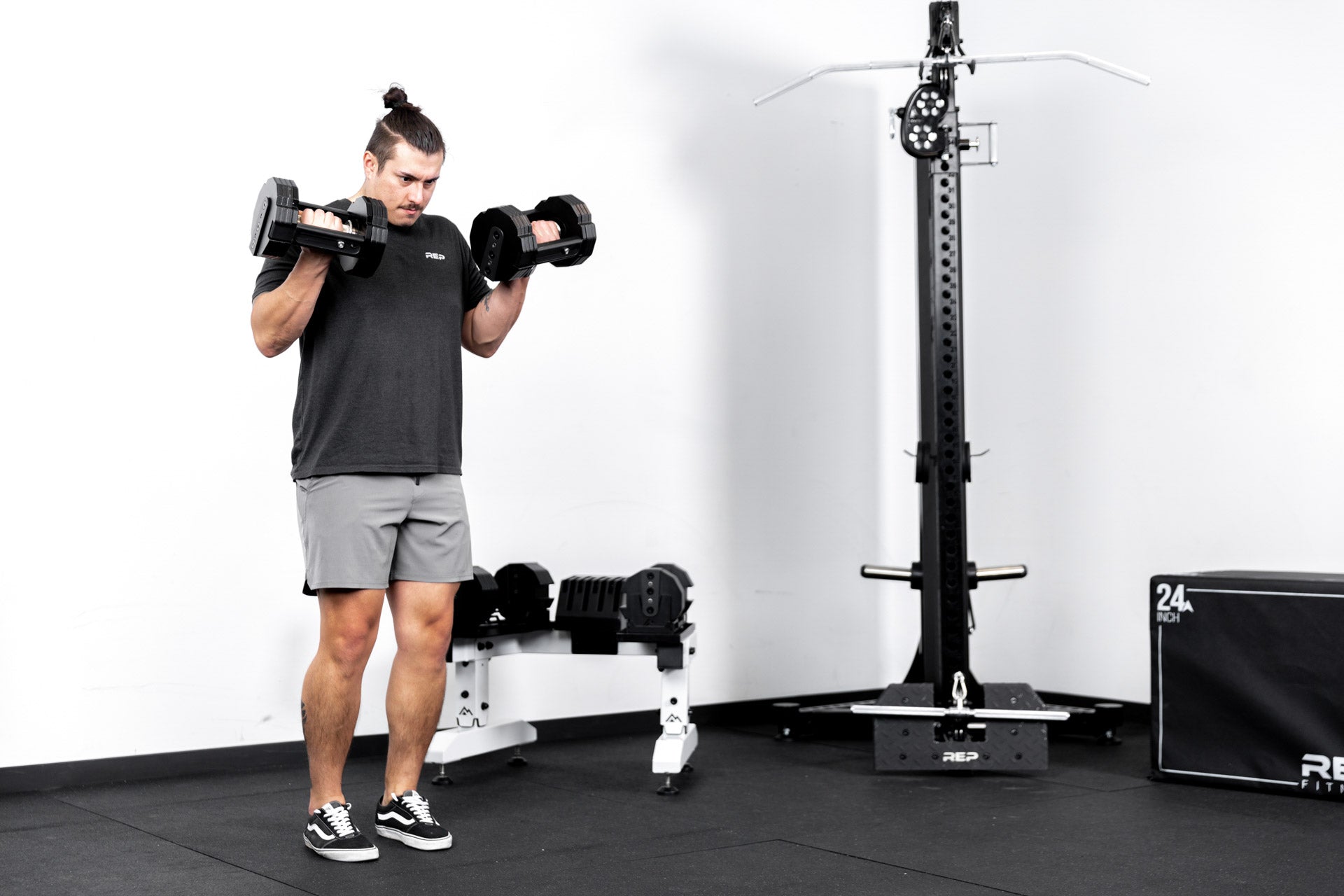 Athlete working out with REP® x PÉPIN™ adjustable dumbbells in front of a white REP® Adjustable Dumbbell Stand