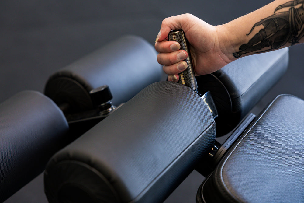 Athlete gripping the knurled handle on the Adjustable Bench Leg Roller Attachment 2.0