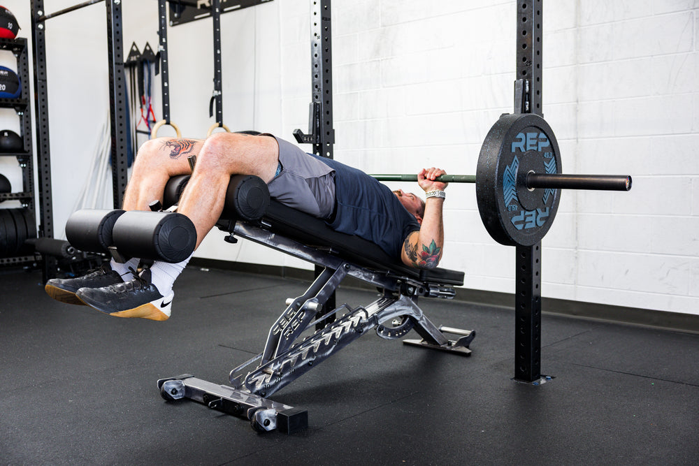 Athlete decline bench pressing with the Adjustable Bench Leg Roller Attachment 2.0