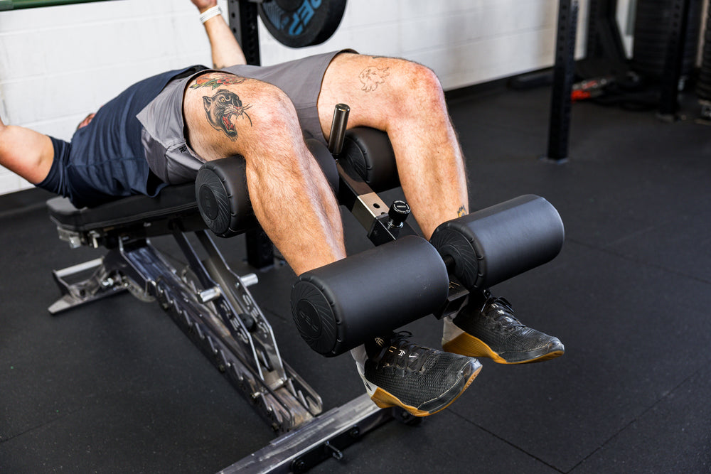 Athlete using the Adjustable Bench Leg Roller Attachment 2.0 for decline bench press