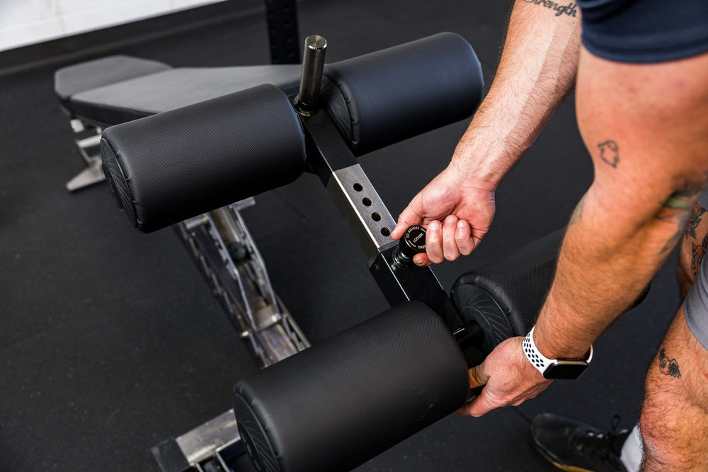 Athlete adjusting the length on the Adjustable Bench Leg Roller Attachment 2.0