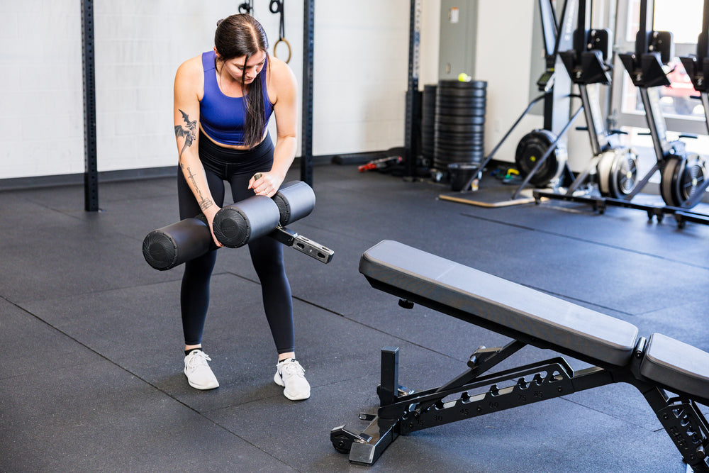 Athlete installing the Adjustable Bench Leg Roller Attachment 2.0