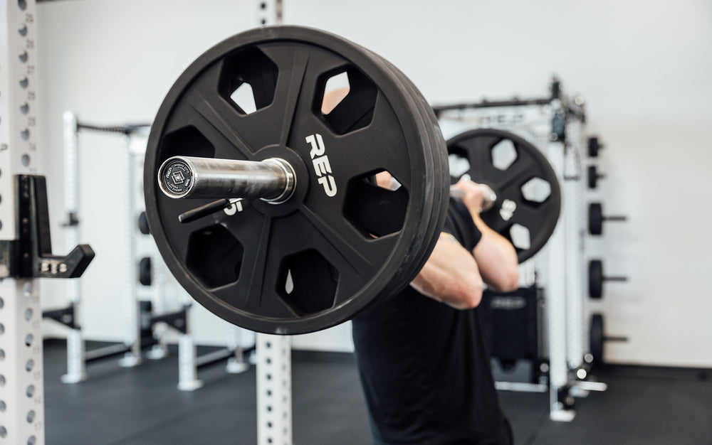 Close-up side view of a REP Double Black Diamond Power Bar in the back rack position on a male lifter.