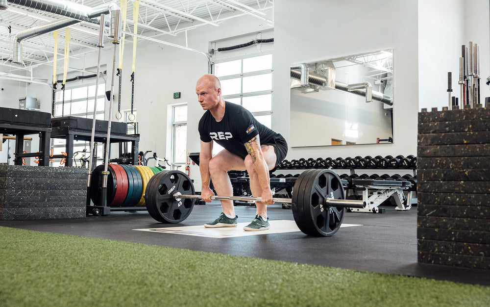 Male lifter in the set-up position about to perform a deadlift with a REP Double Black Diamond Power Bar.