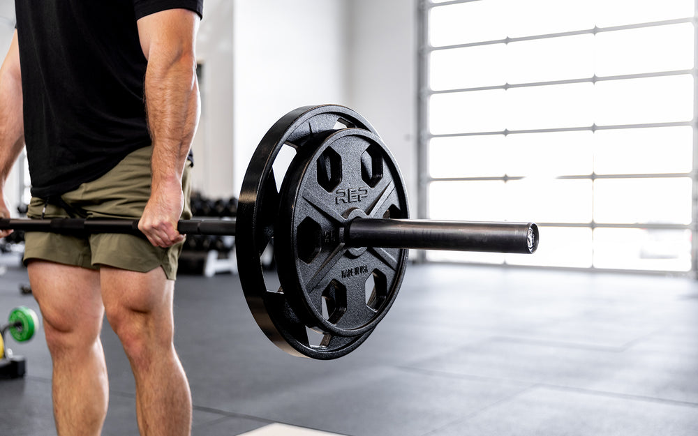 Lifter performing a deadlift with a barbell loaded with a pair of 45lb and 25lb USA-Made Equalizer Iron Plates.