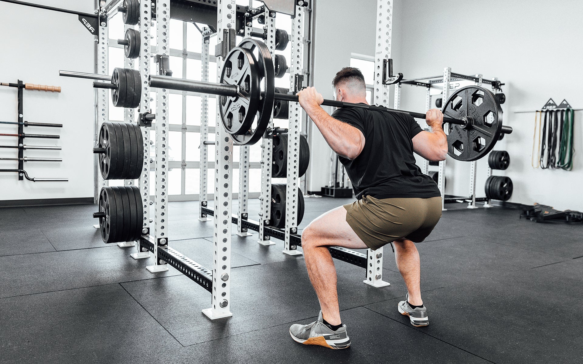 Lifter performing a back squat with a barbell loaded with a pair of 45lb and 35lb USA-Made Equalizer Iron Plates.