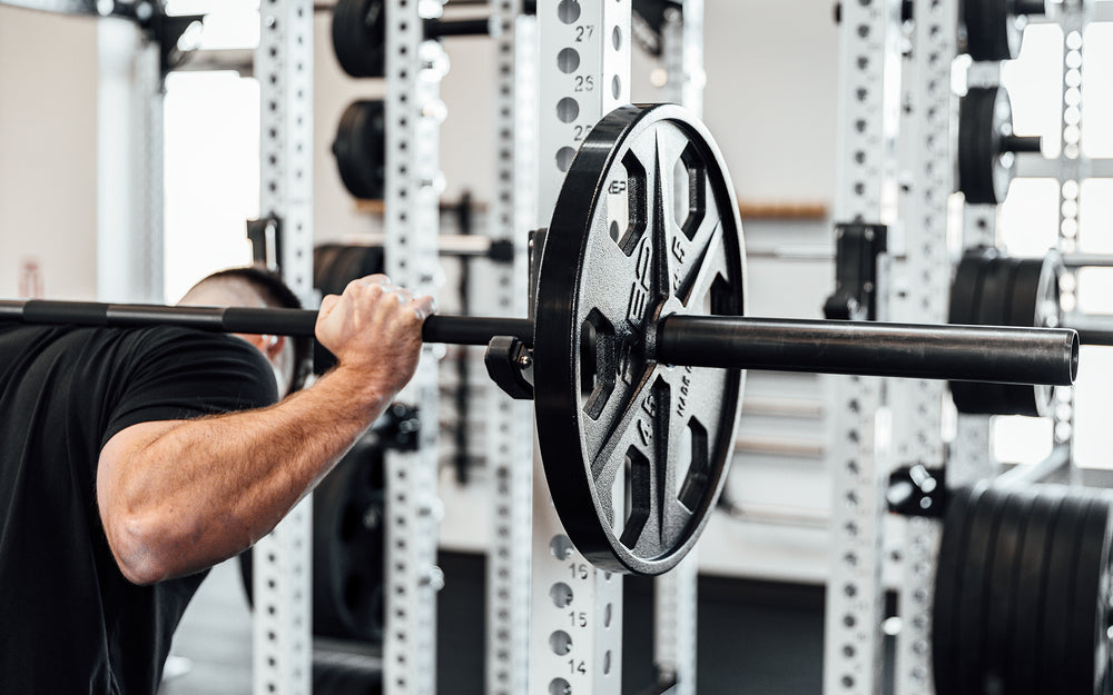 Lifter getting ready to perform a back squat with a barbell loaded with a pair of 45lb USA-Made Equalizer Iron Plates.