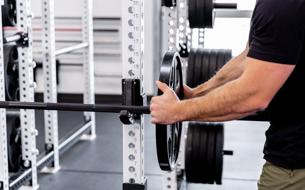 Lifter loading a racked barbell with a 45lb USA-Made Equalizer Iron Plate.