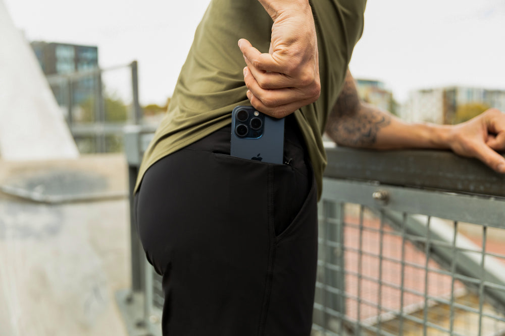 Athlete slipping their phone into the zipper pocket on the Men's Felix Pants 2.0